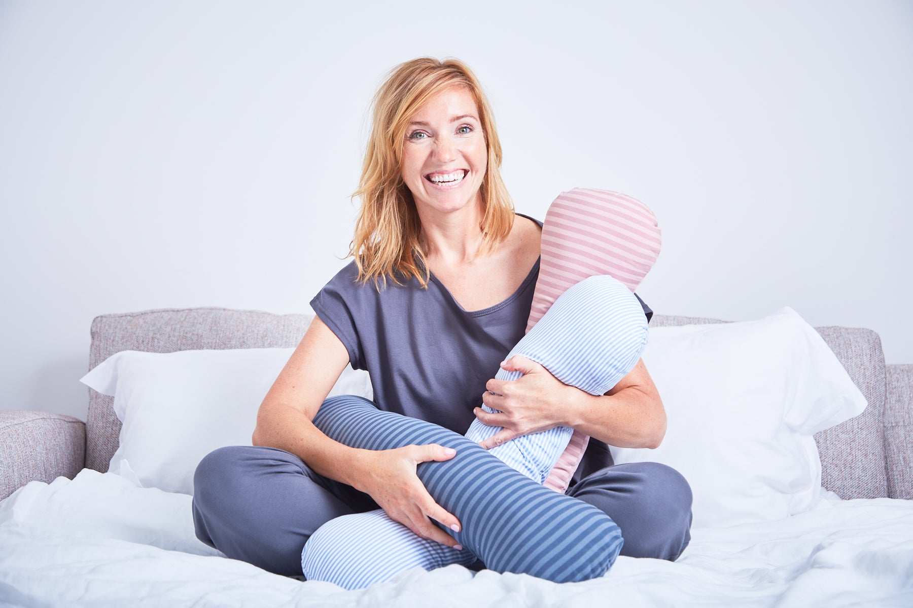 Adult women holding three different coloured sleep pillows