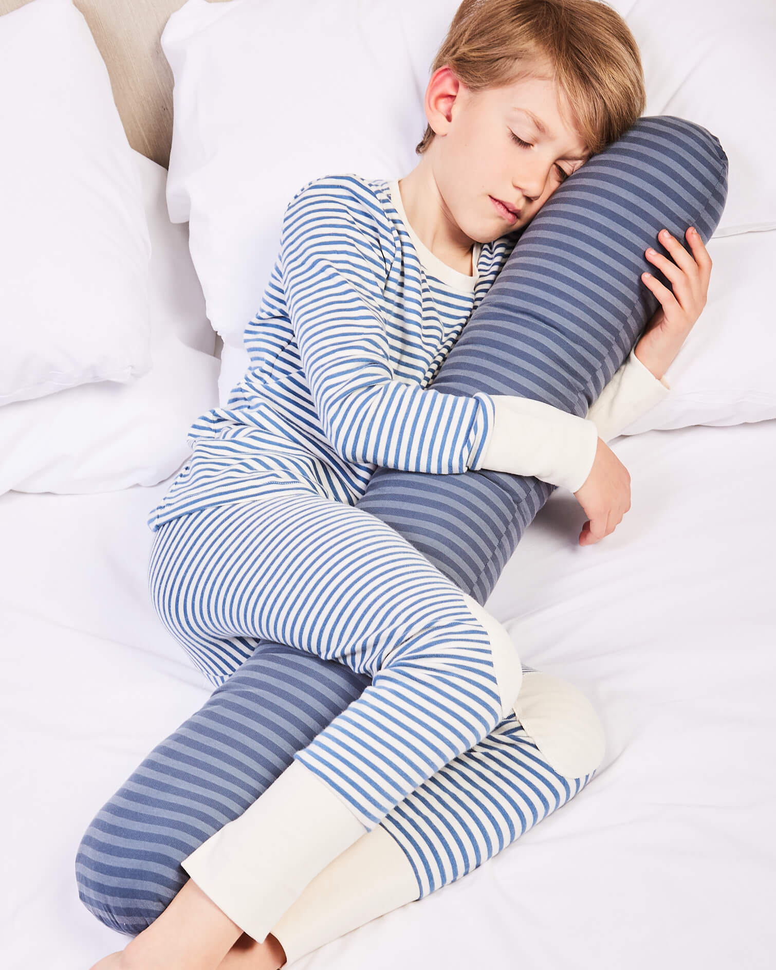 Young boy hugging his navy blue sleeping pillow