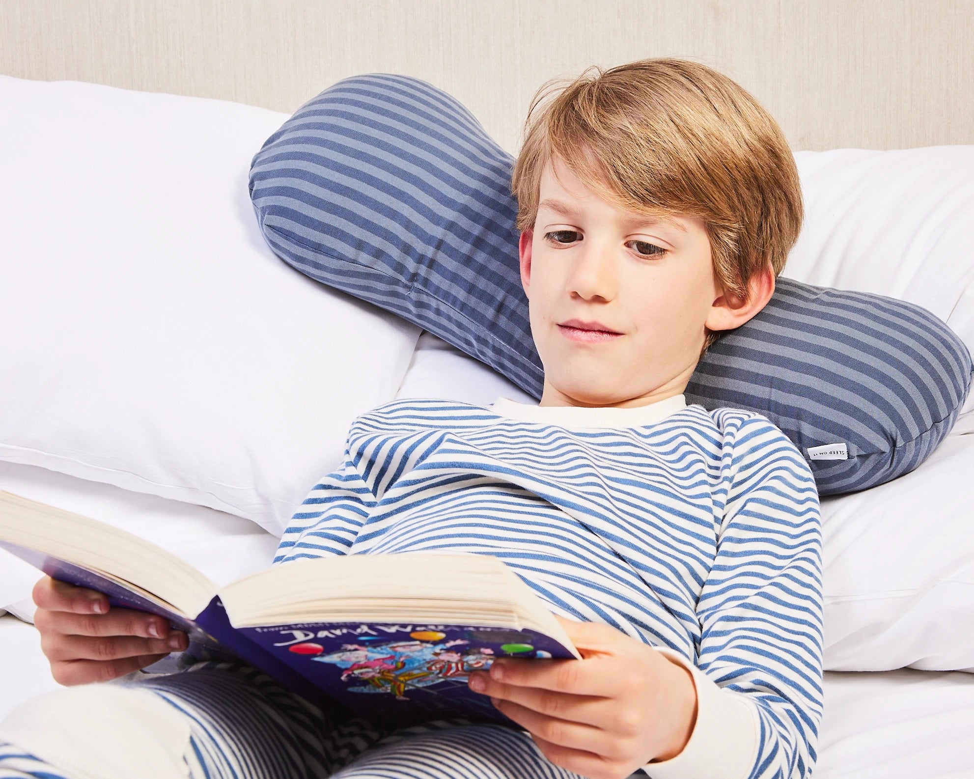 Young boy using short sleeping pillow to read with ease