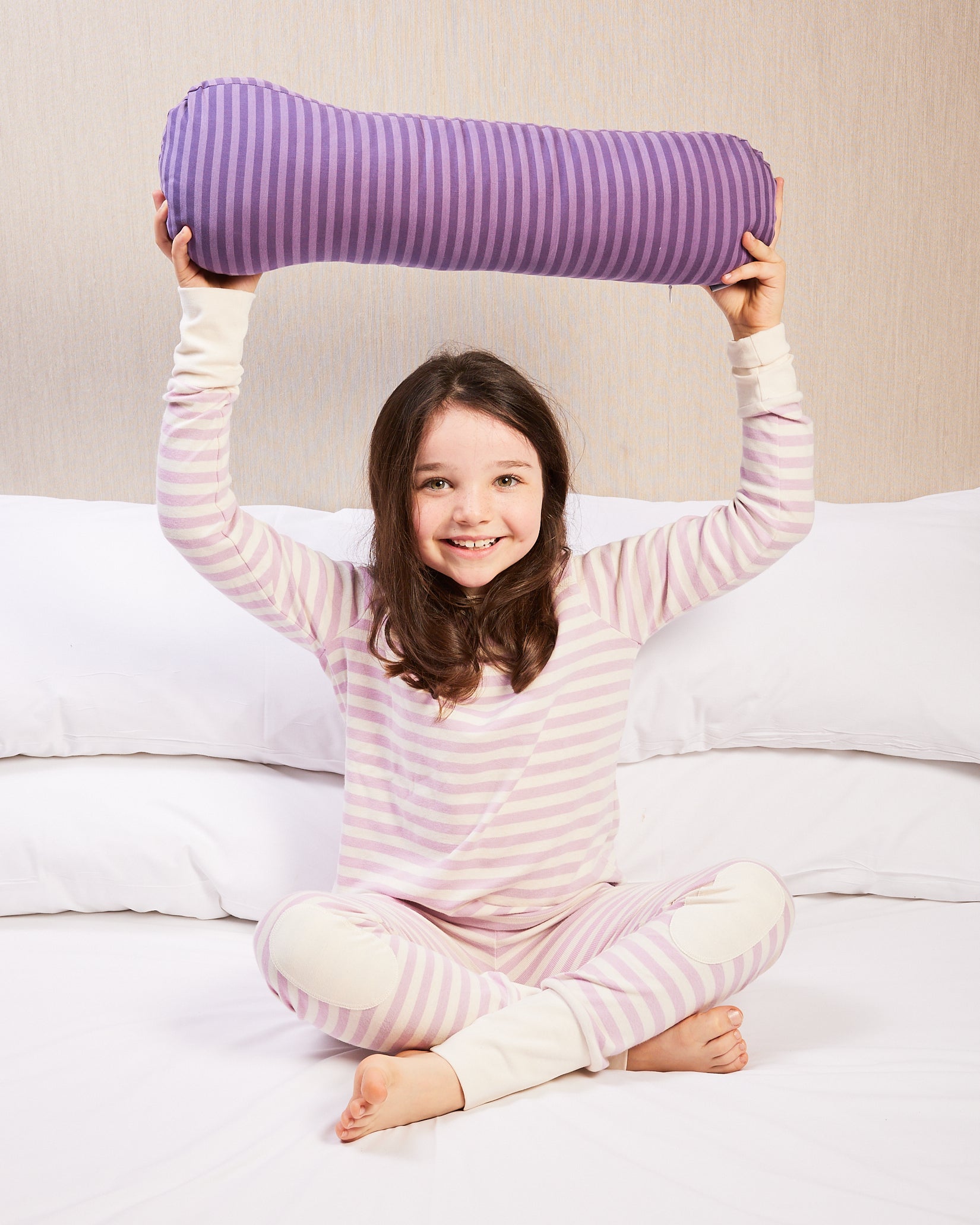 Young girl holding a weighted short pillow above her head